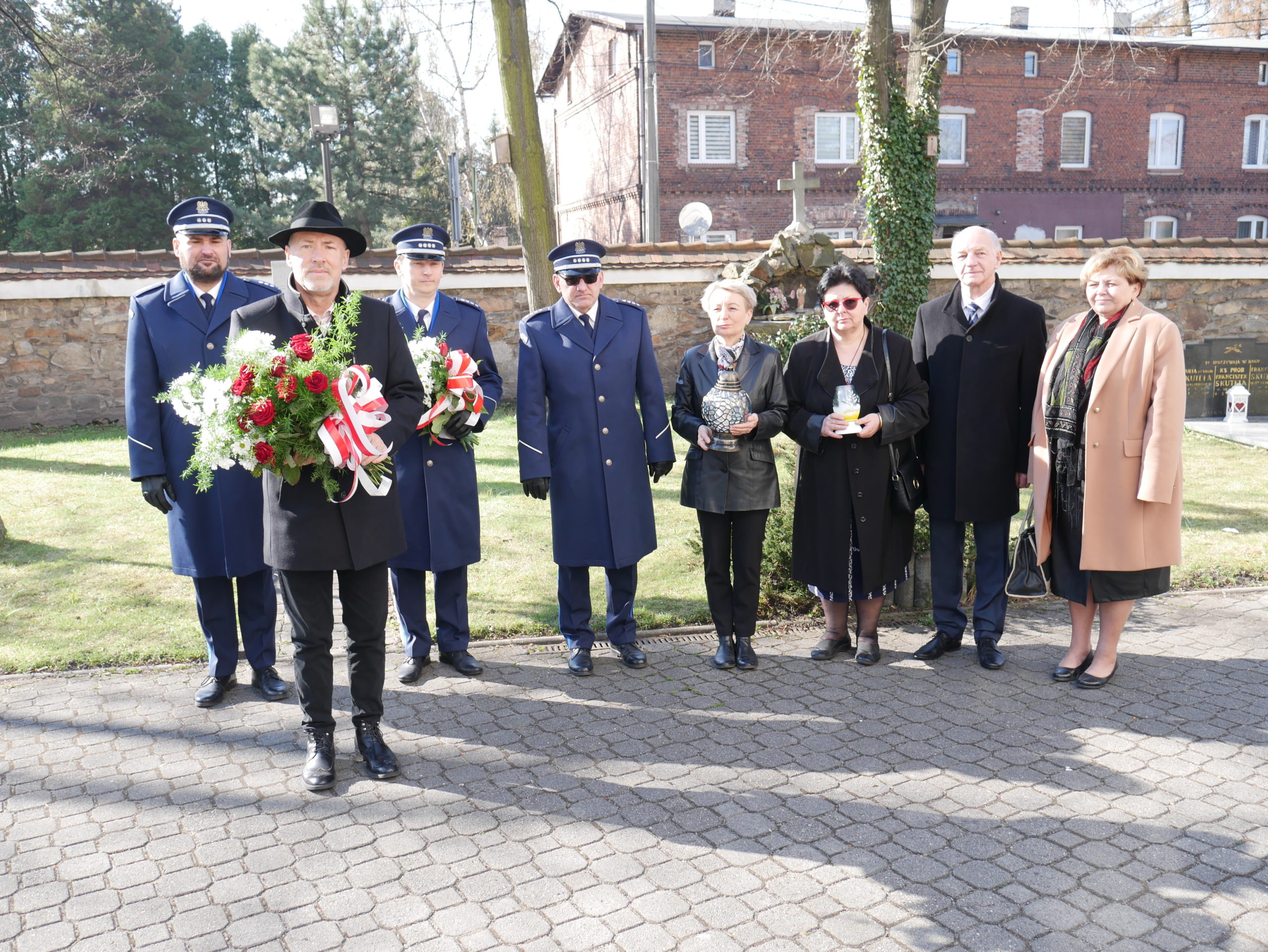 Zarząd Powiatu oraz policjanci stoją z kwiatami pod pomnikiem