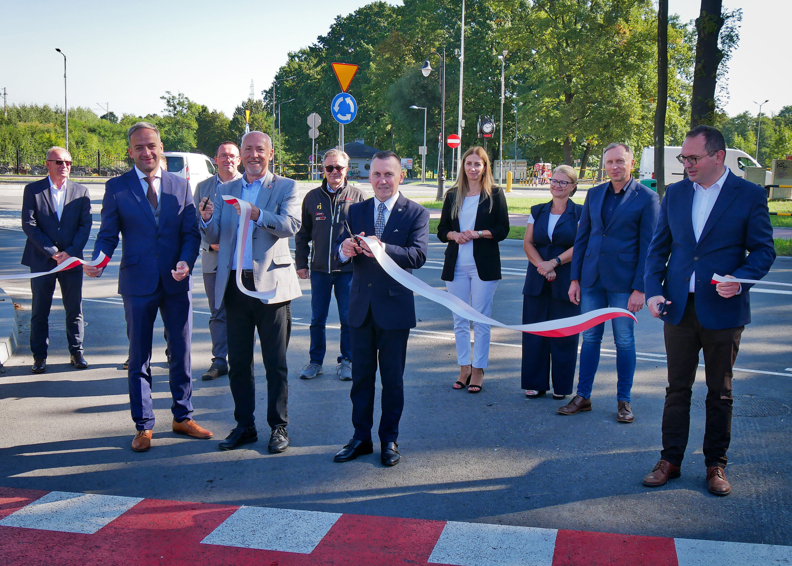 Uśmiechnięta grupa oficjeli pozuje do zdjęcia po przecięciu wstęgi