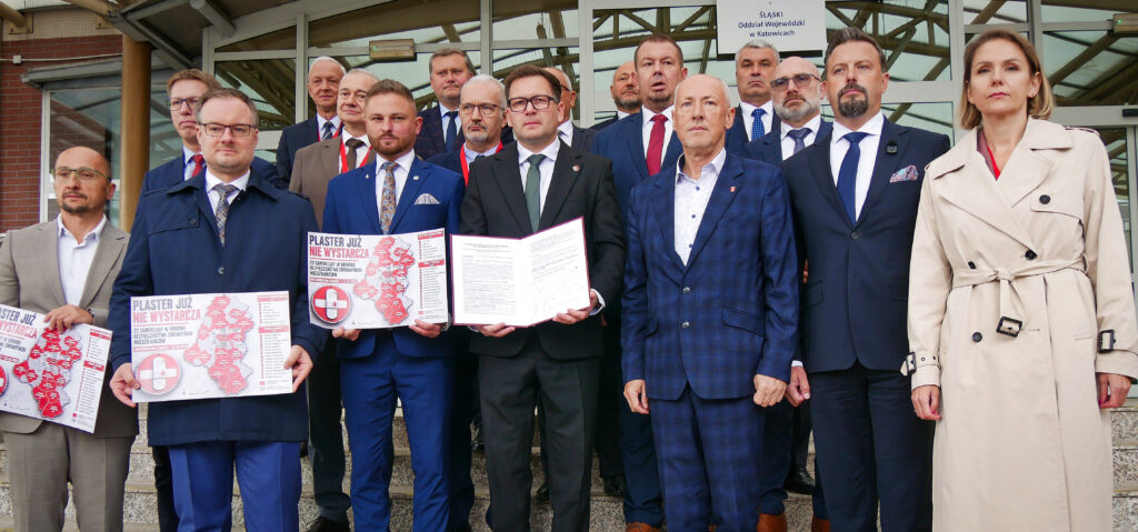 Prezydenci miast i starostowie pozują do zdjęcia na schodach OW NFZ w Katowicach