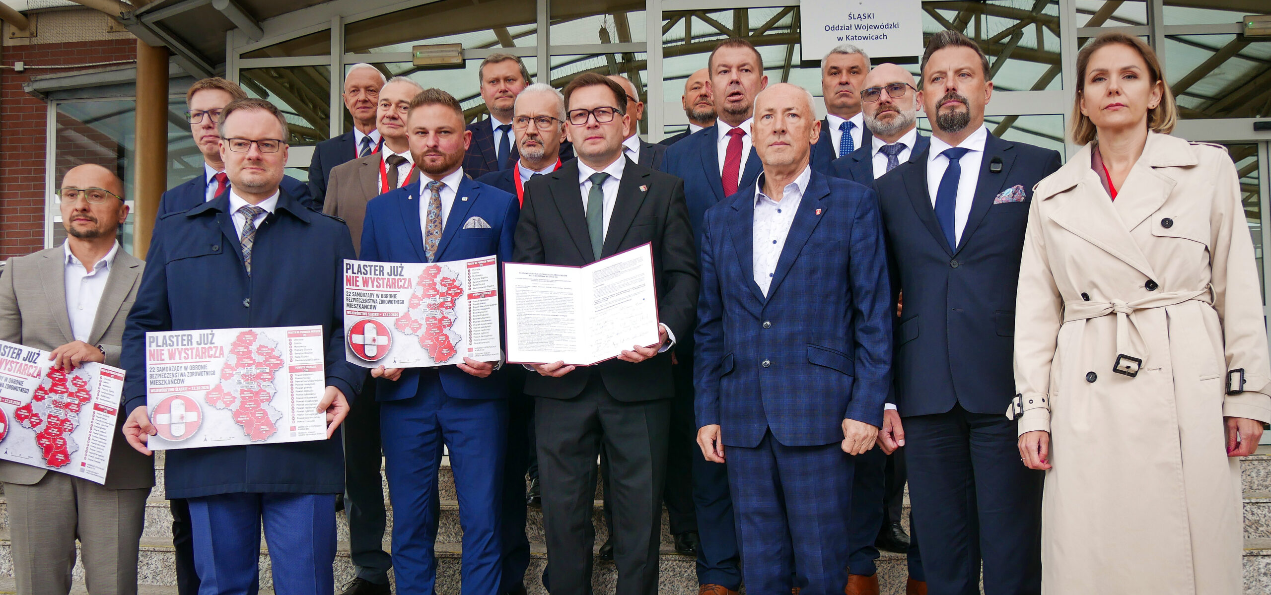 Prezydenci miast i starostowie pozują do zdjęcia na schodach OW NFZ w Katowicach